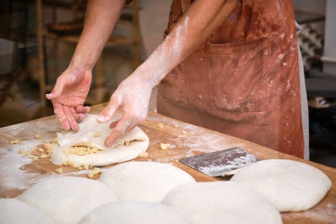 Detail of a baker's hands introducing ingredients into the bread