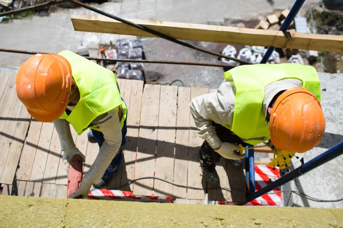 Top view of two men with orange bump caps standing on a scaffolding