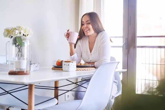 Smiling woman eating at table at home