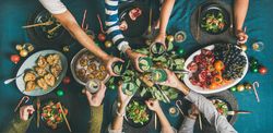 Group toasting at festive table with candy canes and roasted pears, wide composition