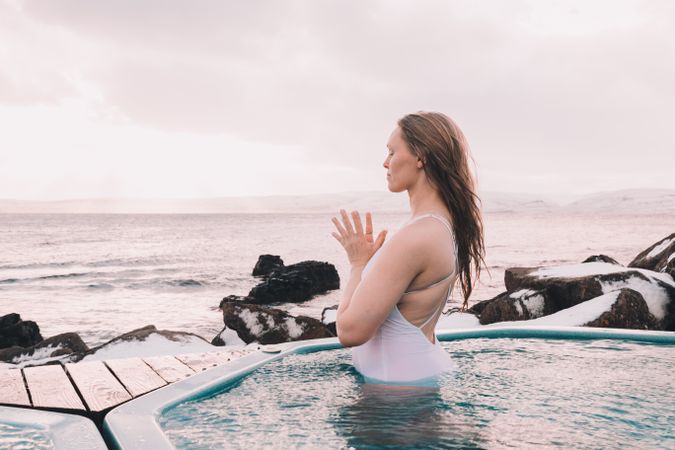 Woman sitting in pool near stones