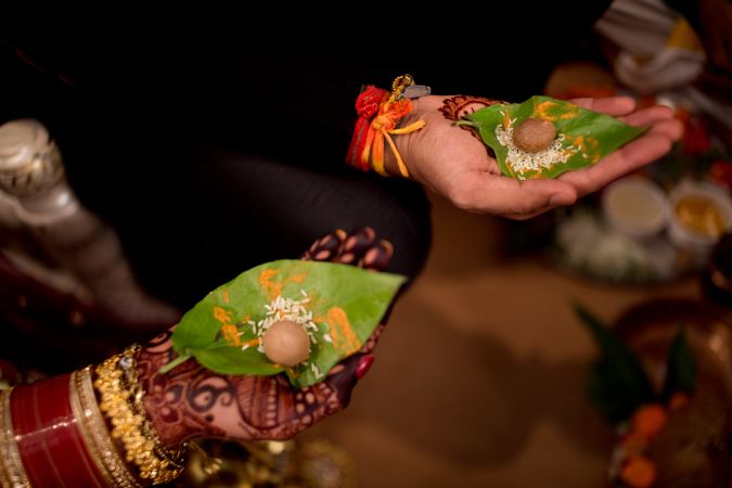 Indian Bride and Groom holding green leaves with rise and seed on them