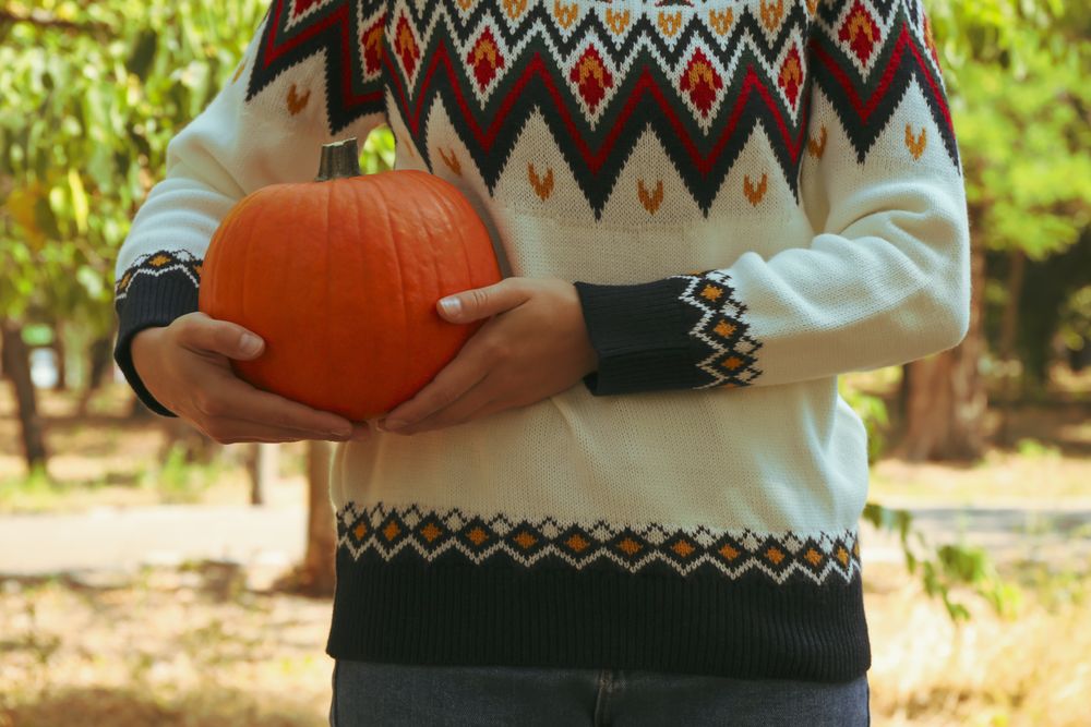 Woman in sweater and jeans hold pumpkin outdoor