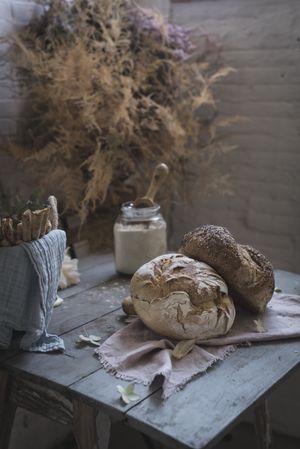 Fresh bread on served table and bunch of dry plant hanging on thread