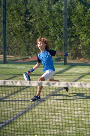 Active boy playing padel on court