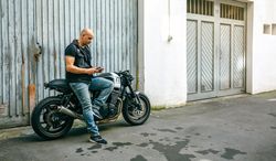 Biker looking mobile sitting on motorcycle