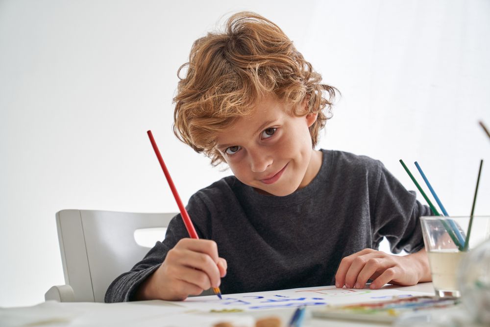 Cheerful boy painting at table