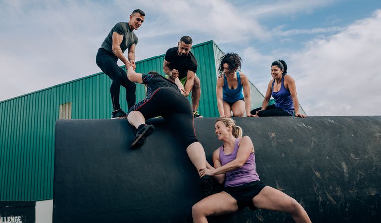 Participants in an obstacle course climbing a drum