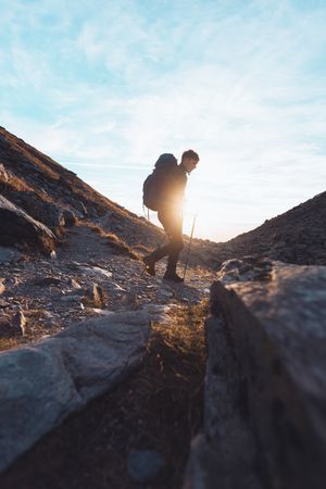 Side view of a man with backpack hiking in Switzerland at sunrise