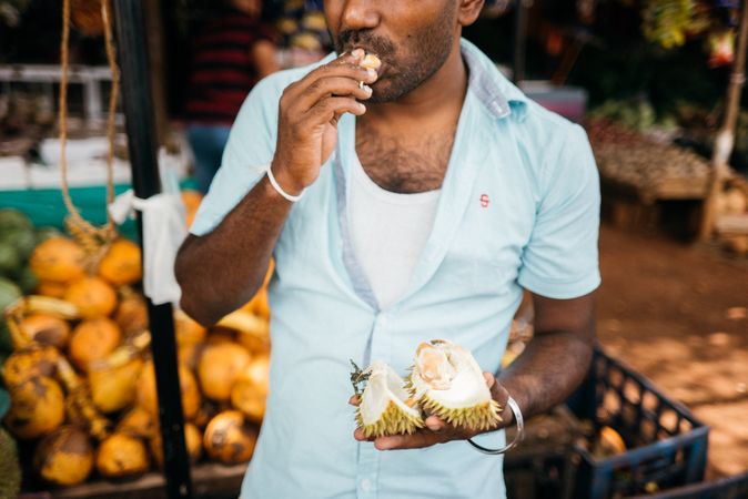 Sri Lankan eating open durian fruit at market