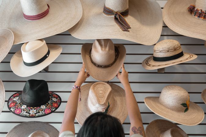 A young Hispanic woman is choosing a hat in a shop