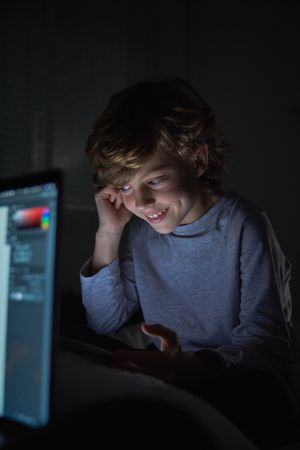 Content boy doing homework in darkness