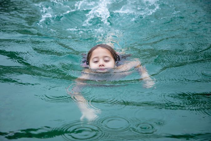 child swimming with closed eyes in lake