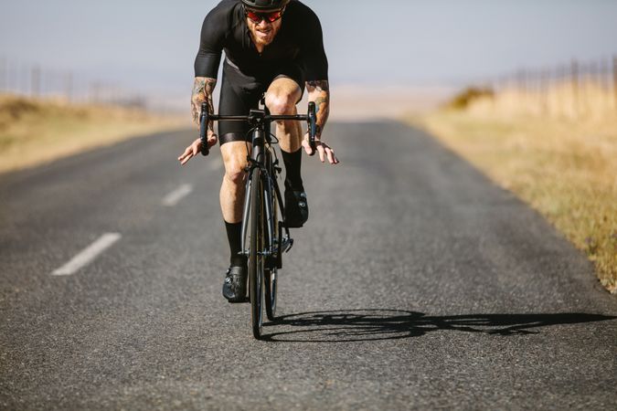 Male athlete cycling on country road