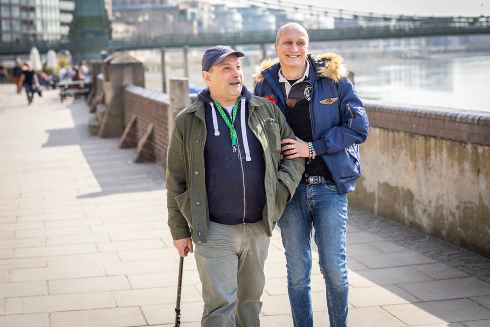Two male friends laughing and walking by the river and talking