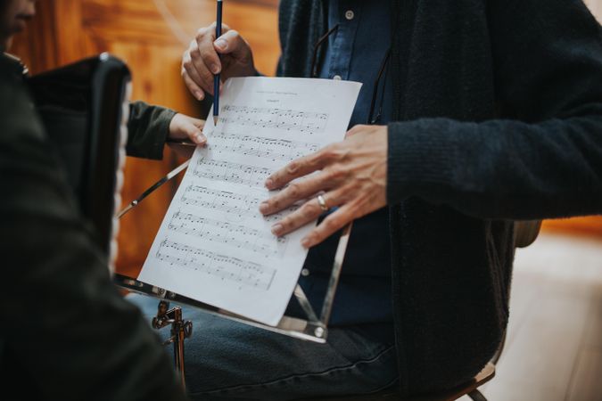 Cropped shot of male teacher using pencil to point to music note on sheet music