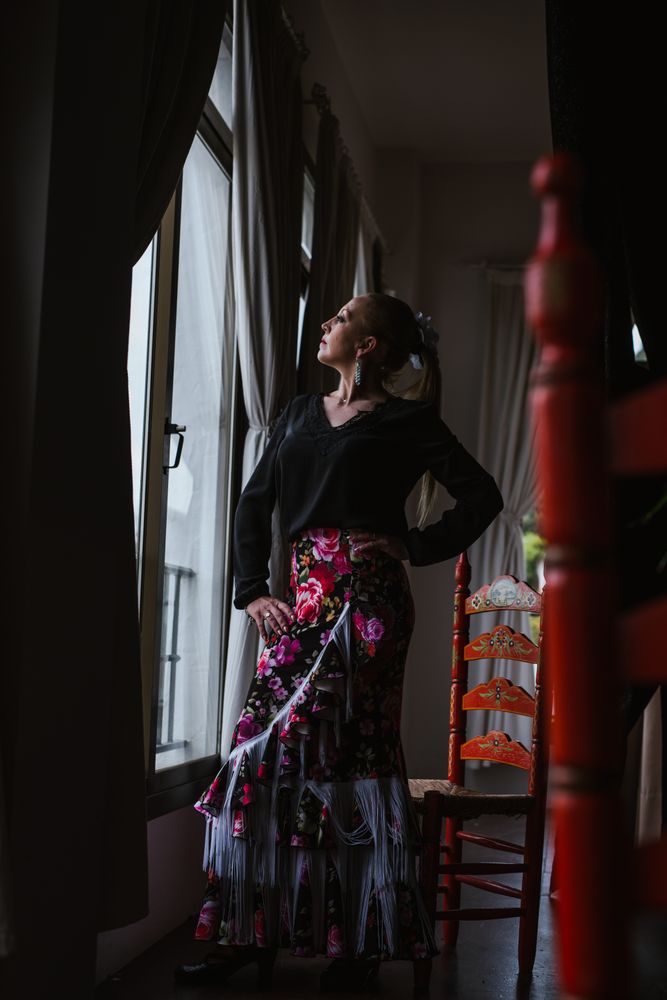 Woman dancer in suit for flamenco sitting and looking out window