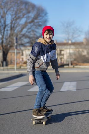 Teenager wearing a hat skateboarding on the street