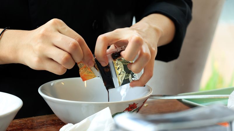 Female Hand Pouring Seasoning Package for Indomie Instant Noodles