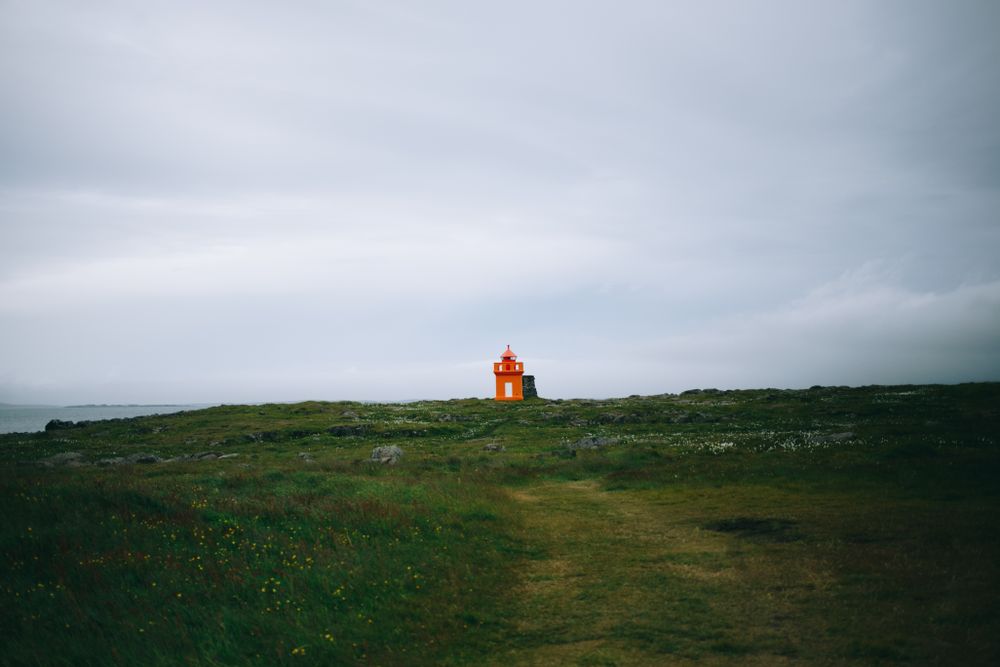 Solitary orange lighthouse on cloudy day