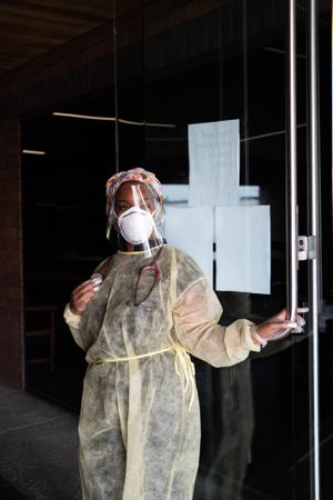 Three quarter length shot of woman nurse holding the door of medical building open