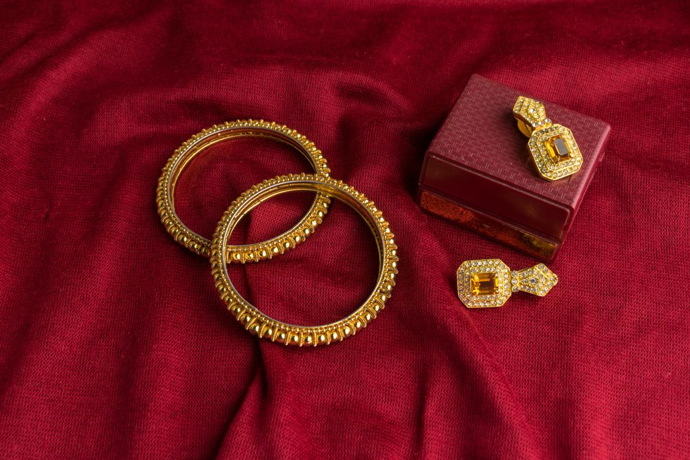 Beautiful shiny golden bangles and diamond studded traditional earrings on a red velvet background