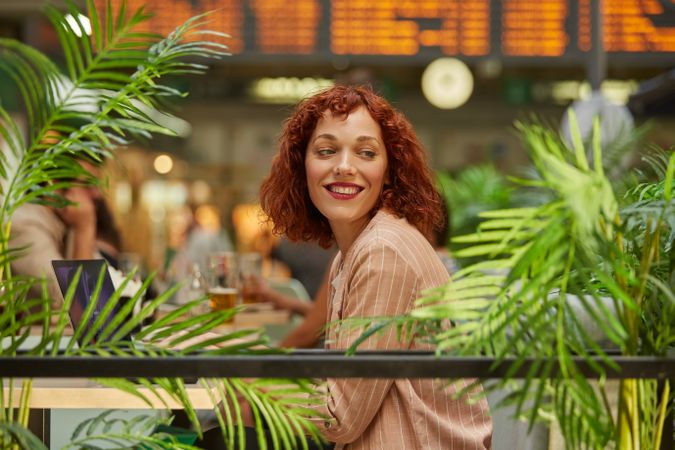 Cheerful young woman working on laptop in cafe