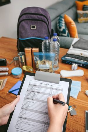 Woman doing checklist of emergency backpack