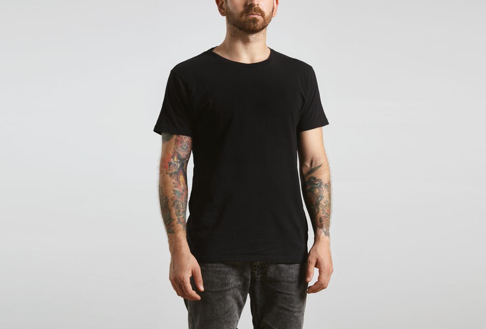 Tattooed man in dark clothes on light background
