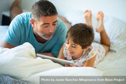 Father with child playing on tablet in bed 4dRLa0