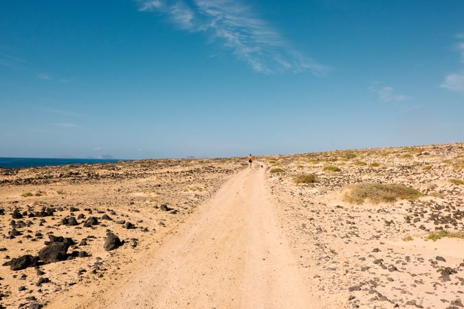 Back of woman in distance walking on sandy road