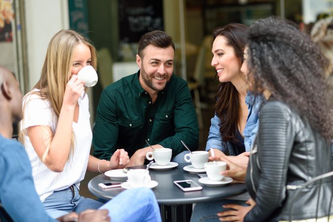 Group of friends sipping coffee together at outdoor cafe