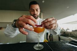 Cheerful man preparing a cocktail in a bar.