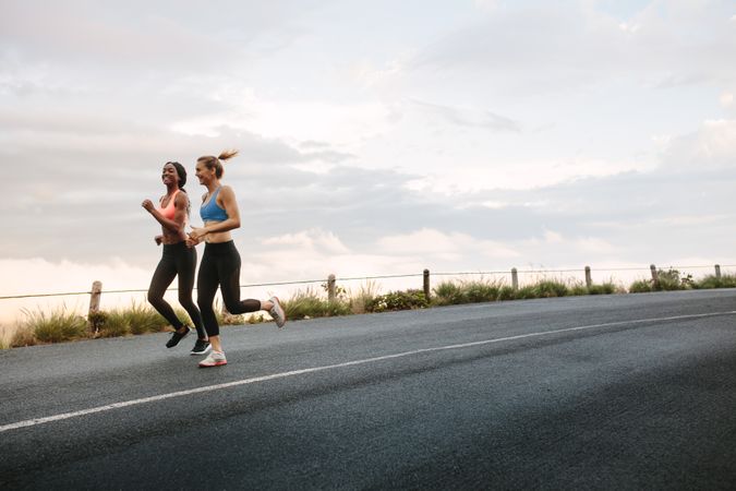 Two fit women running on road
