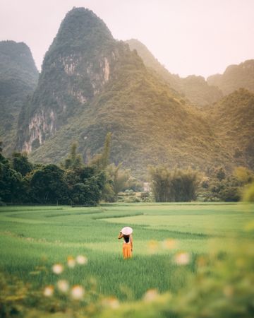 Back view of woman with conical hat standing against mountainous landform