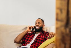 Black man making a call with smartphone relaxed at home