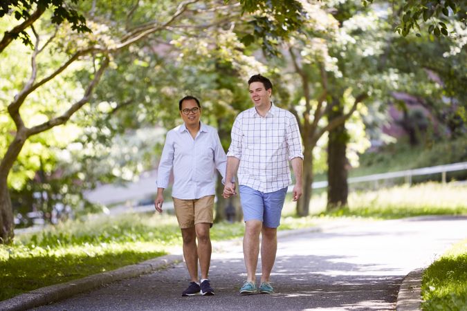 Two men holding hands and walking between trees