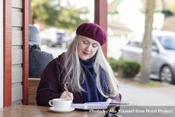 Woman reflecting her thoughts into a notebook at a coffee shop 5ogVm5