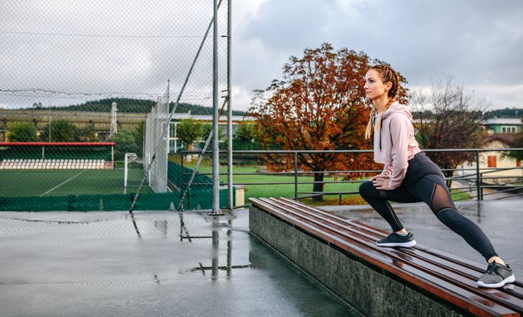 Young sportswoman stretching legs outdoors
