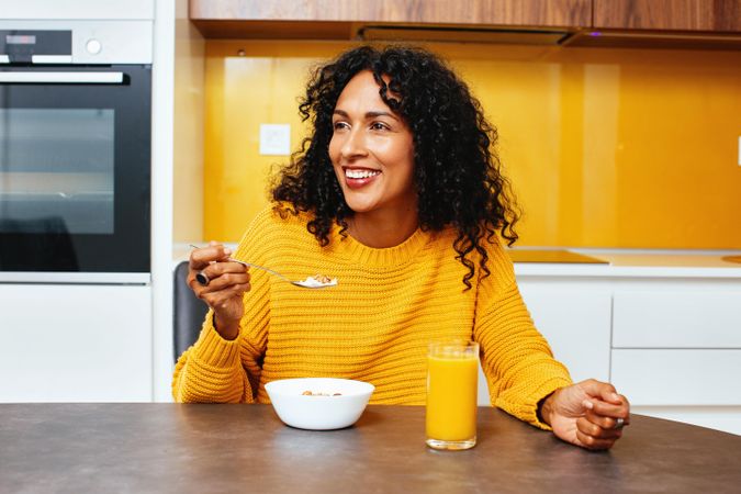Woman in colorful kitchen with a cereal bowl and orange juice