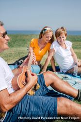 Family on outdoor picnic with ukulele, vertical 0Wvojb