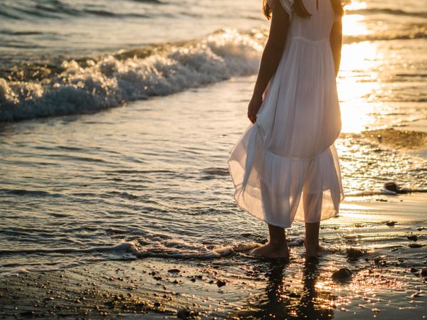 Adorable girl walking on seaside at sunset