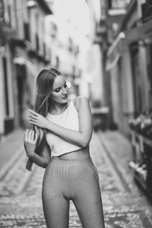 Chic woman arranging her hair in the street in B&W