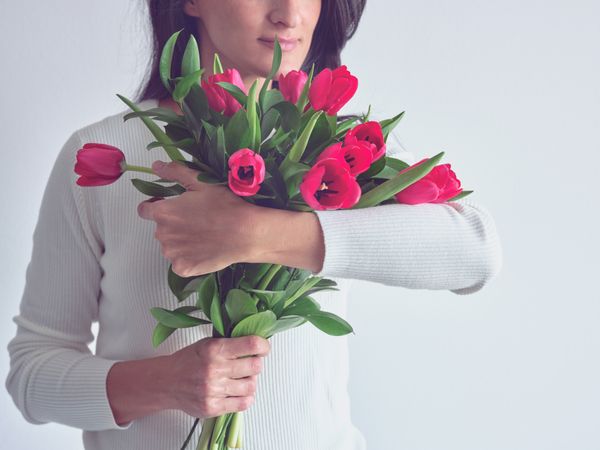 Crop woman embracing beautiful fresh bouquet of tulips