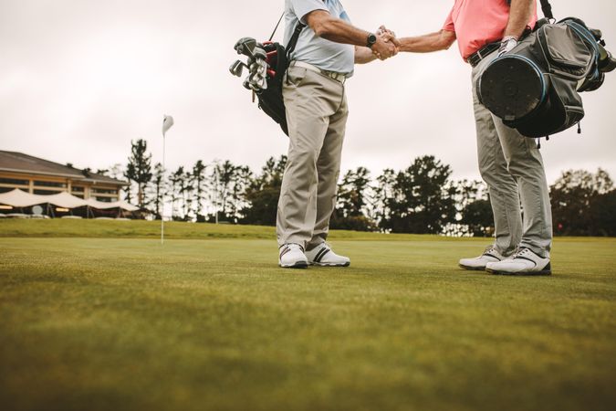 Two men shaking hands on a golf course