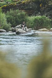 Confident man fishing with rod while standing in river stream