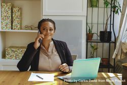 Female business owner concentrating on phone call in her home office 5rjzl5