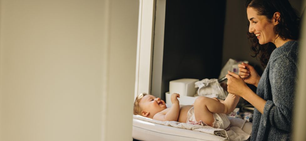 Loving mother talking with her baby lying on changing table