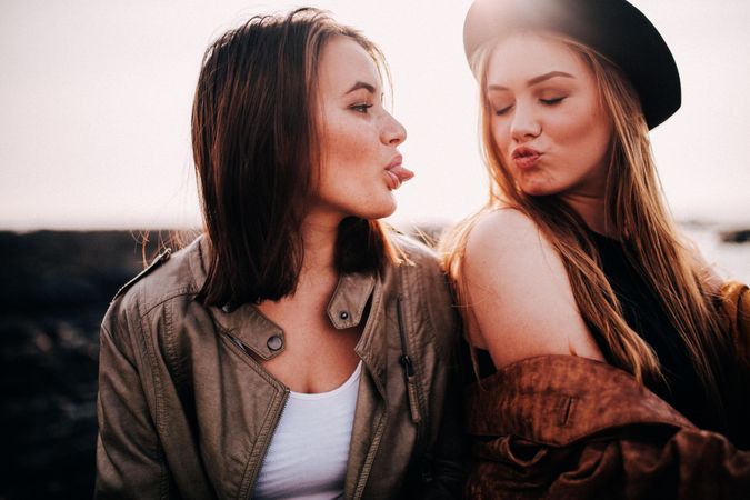 Two young women making silly faces at each other outside