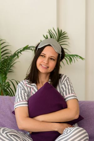 Woman in striped pajamas holding pillow, relaxing at home.